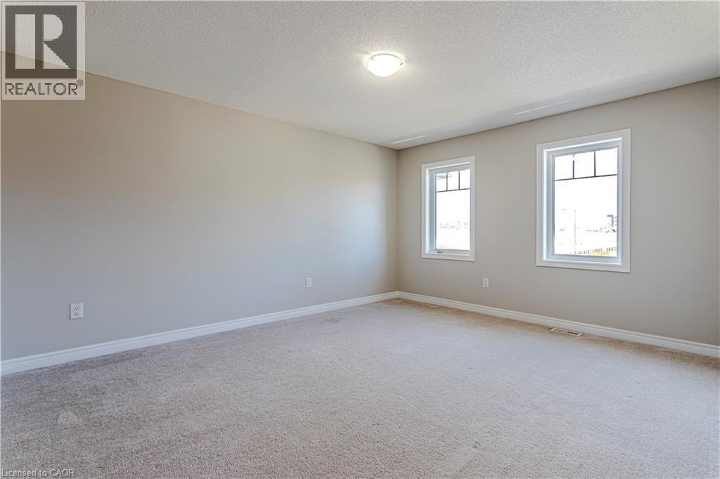 Spacious room featuring neutral carpeting, light-toned wall paint, crisp white trim, and two bright windows with white frames - 3896 Tufgar Crescent, Burlington, ON