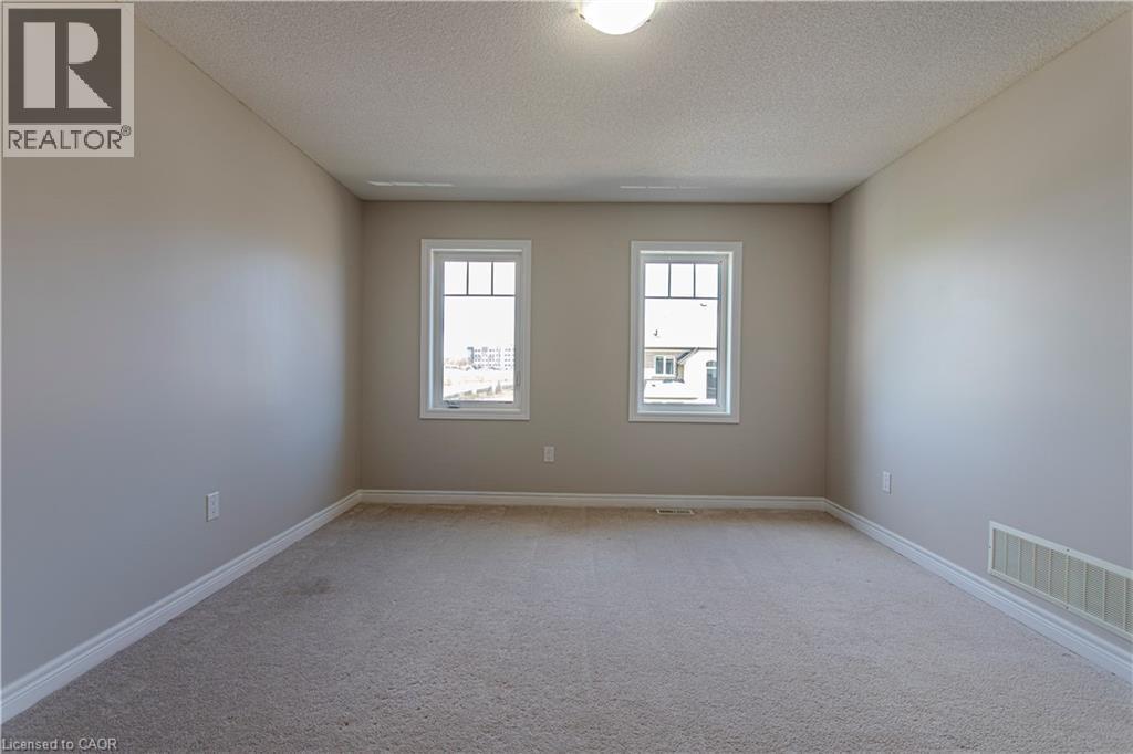 Carpeted room featuring two white-framed windows with grid patterns, light neutral wall paint, and white baseboards - 3896 Tufgar Crescent, Burlington, ON