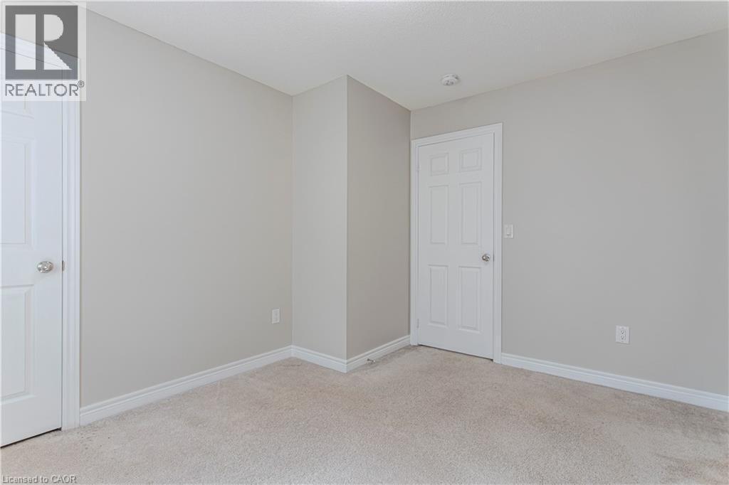 Neutral tone walls featuring white trim, two paneled doors, and light-colored carpeting - 3896 Tufgar Crescent, Burlington, ON