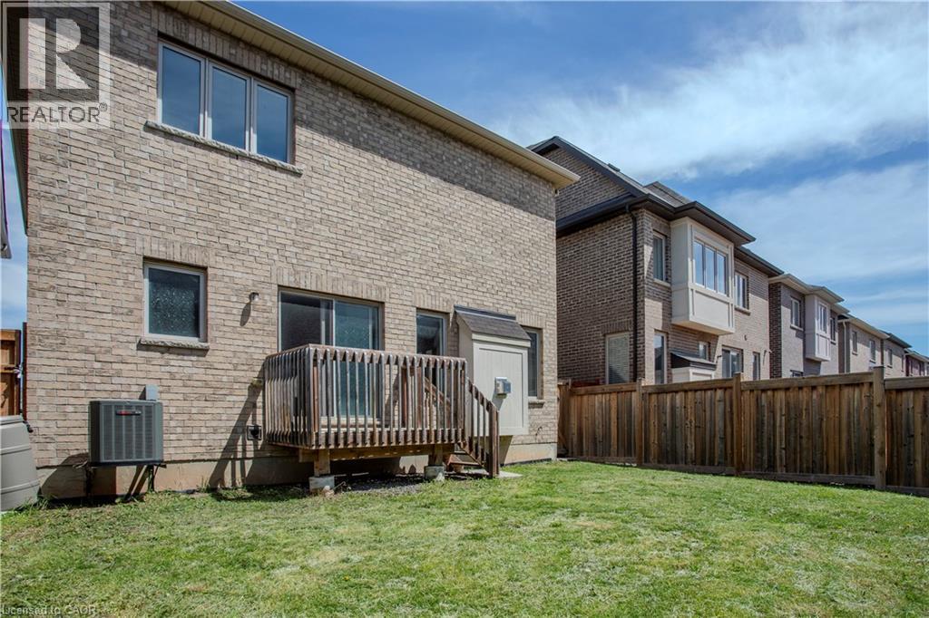 Backyard featuring a wooden deck with railing, a sliding glass door, a brick exterior, and an air conditioning unit - 3896 Tufgar Crescent, Burlington, ON