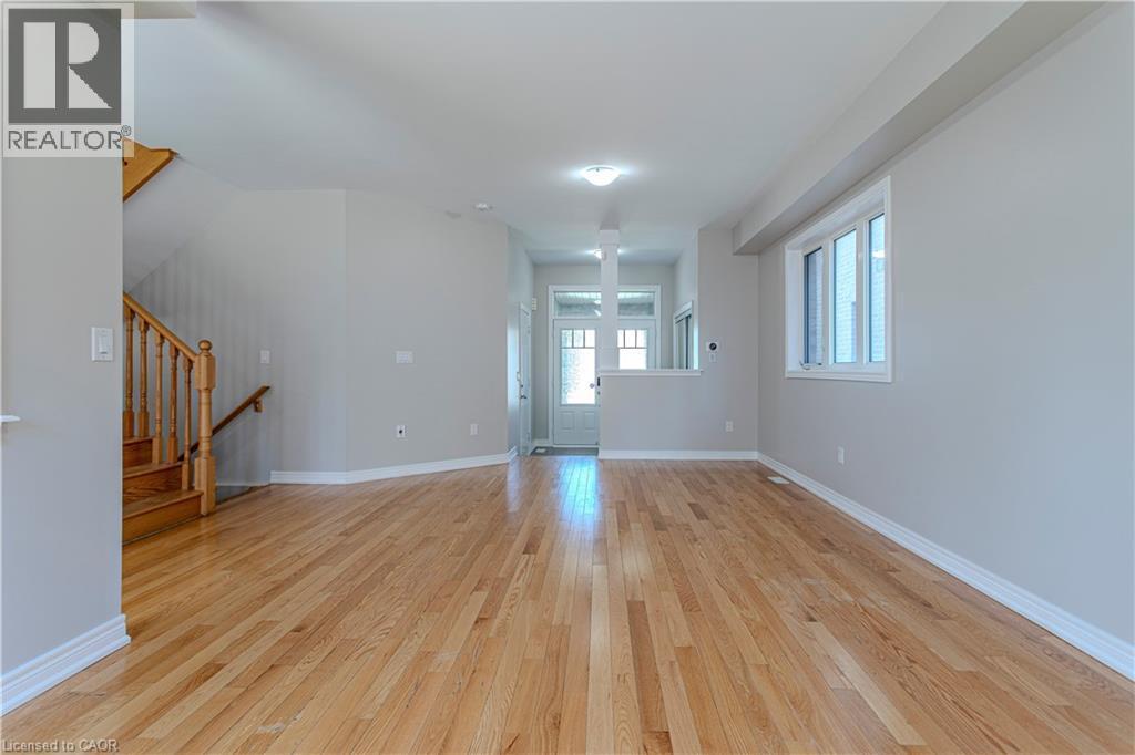 Spacious main level featuring wood-finish flooring, light grey wall tones, and white trim - 3896 Tufgar Crescent, Burlington, ON