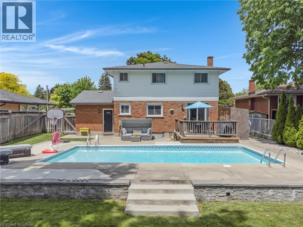 Outdoor swimming pool with concrete surround, multi-level stone retaining wall, and a wooden deck - 139 Dorset Road, Cambridge, ON
