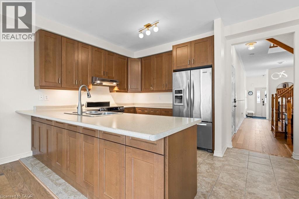 Kitchen featuring wood-finish cabinetry, light-toned countertops, and stainless steel appliances - 4670 Thomas Alton Boulevard, Burlington, ON