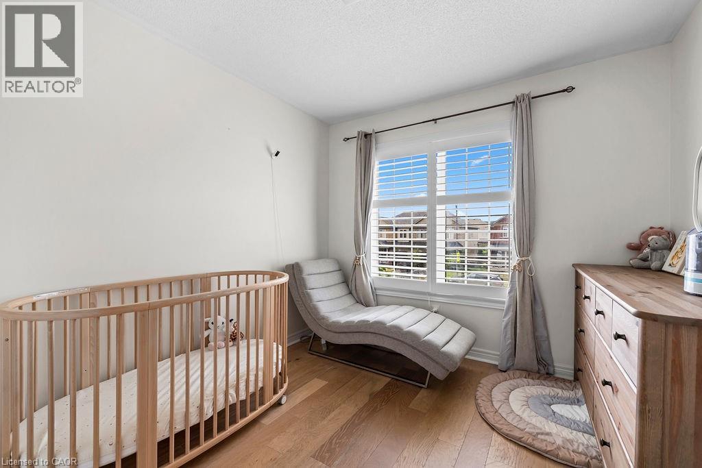 Bright room featuring wood-finish flooring, white walls, and a large window with white louvered blinds - 4670 Thomas Alton Boulevard, Burlington, ON