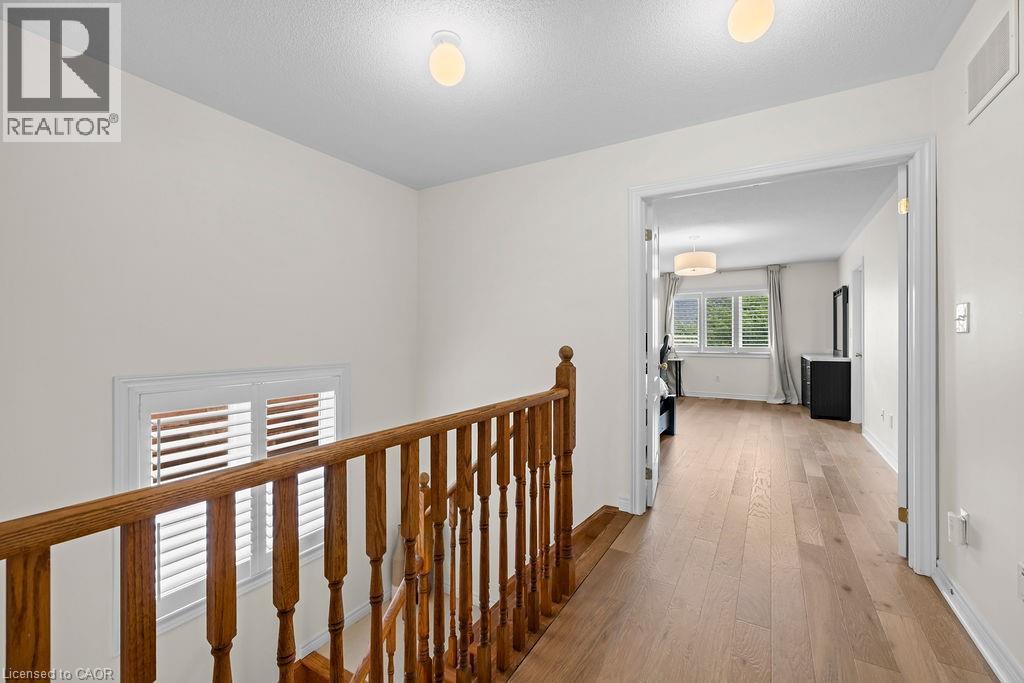 Upper hallway featuring wood-finish flooring and a wood baluster railing - 4670 Thomas Alton Boulevard, Burlington, ON