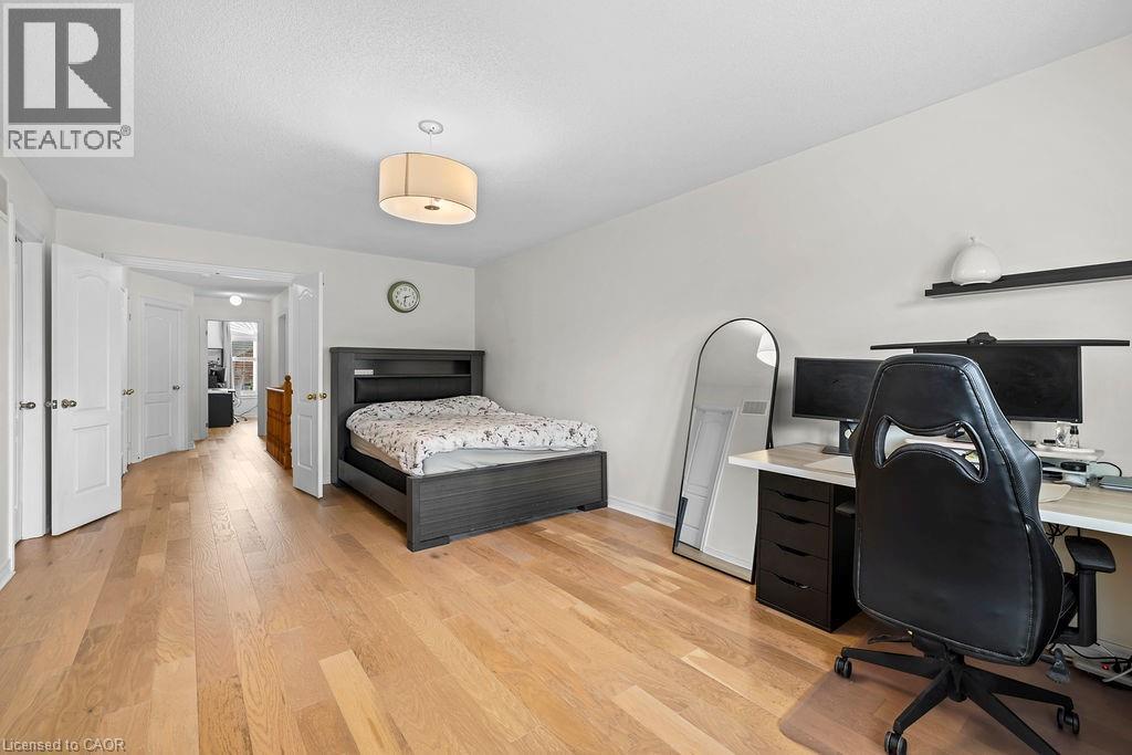 Spacious room featuring light wood-finish flooring, white walls, and a contemporary ceiling light fixture - 4670 Thomas Alton Boulevard, Burlington, ON