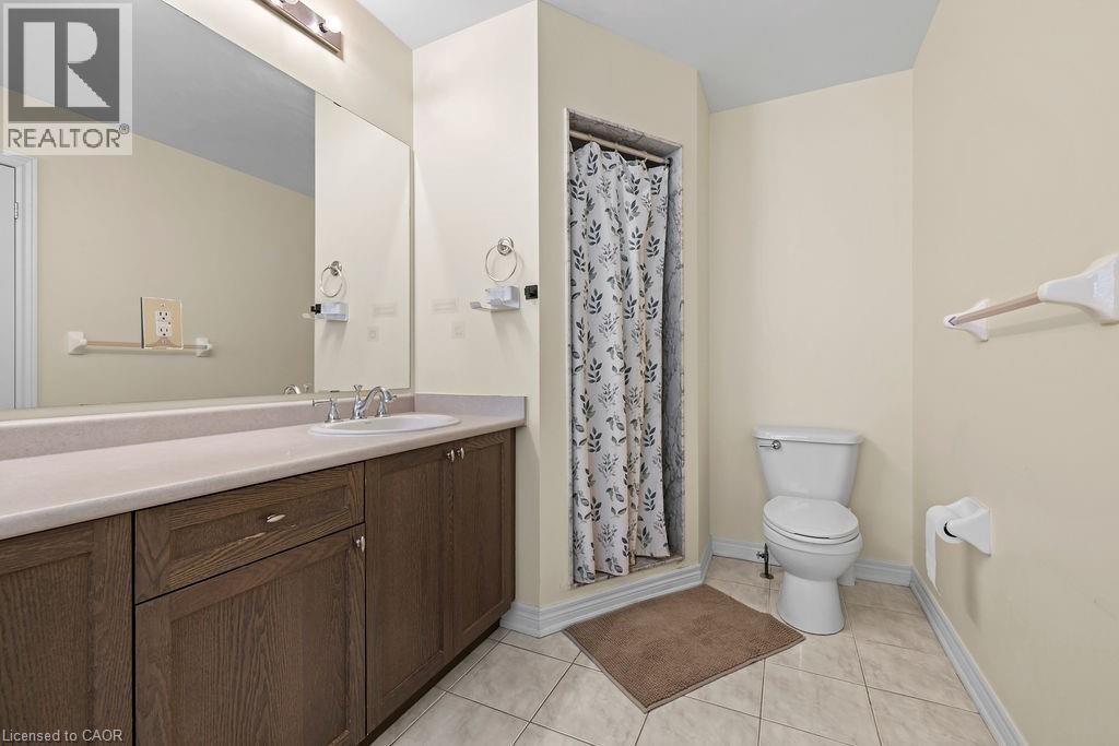 Bathroom featuring a single vanity with a beige countertop, an undermount sink, and dark wood-finish cabinetry - 4670 Thomas Alton Boulevard, Burlington, ON