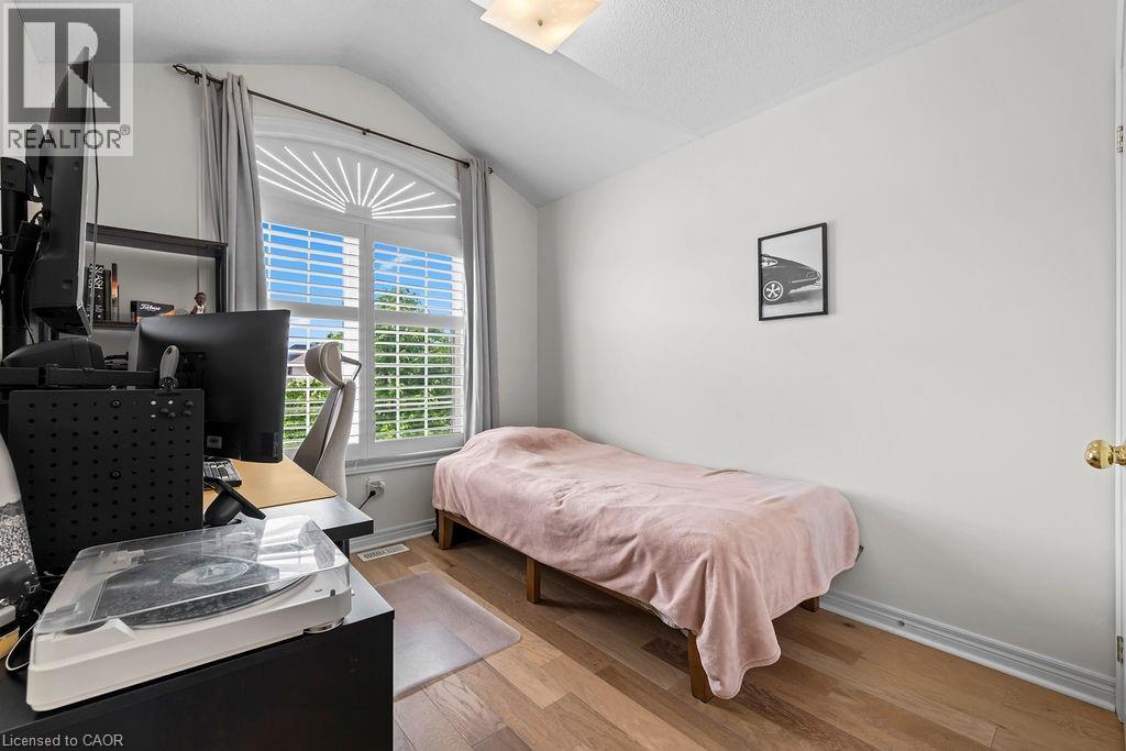 Room featuring a large arched window with white louvered blinds, light wood-finish flooring, and white painted walls - 4670 Thomas Alton Boulevard, Burlington, ON