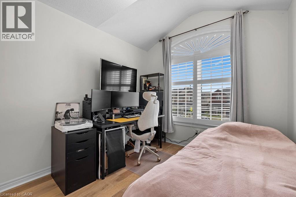 Bedroom featuring an arched window with louvered blinds, light wood-finish flooring, white baseboards, and neutral wall paint - 4670 Thomas Alton Boulevard, Burlington, ON