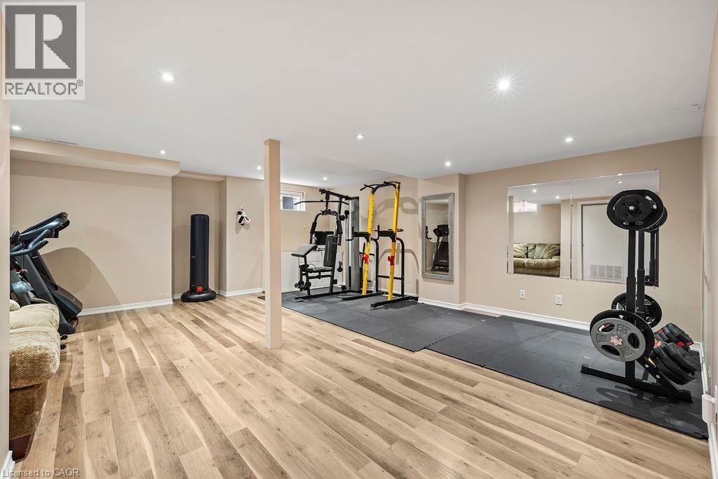 Spacious recreational room featuring wood-finish flooring, recessed lighting, and a neutral color palette - 4670 Thomas Alton Boulevard, Burlington, ON