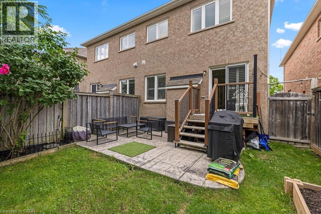 Expansive rear yard featuring a paved patio area, wood deck with stairs, privacy fencing, and a raised garden bed - 4670 Thomas Alton Boulevard, Burlington, ON