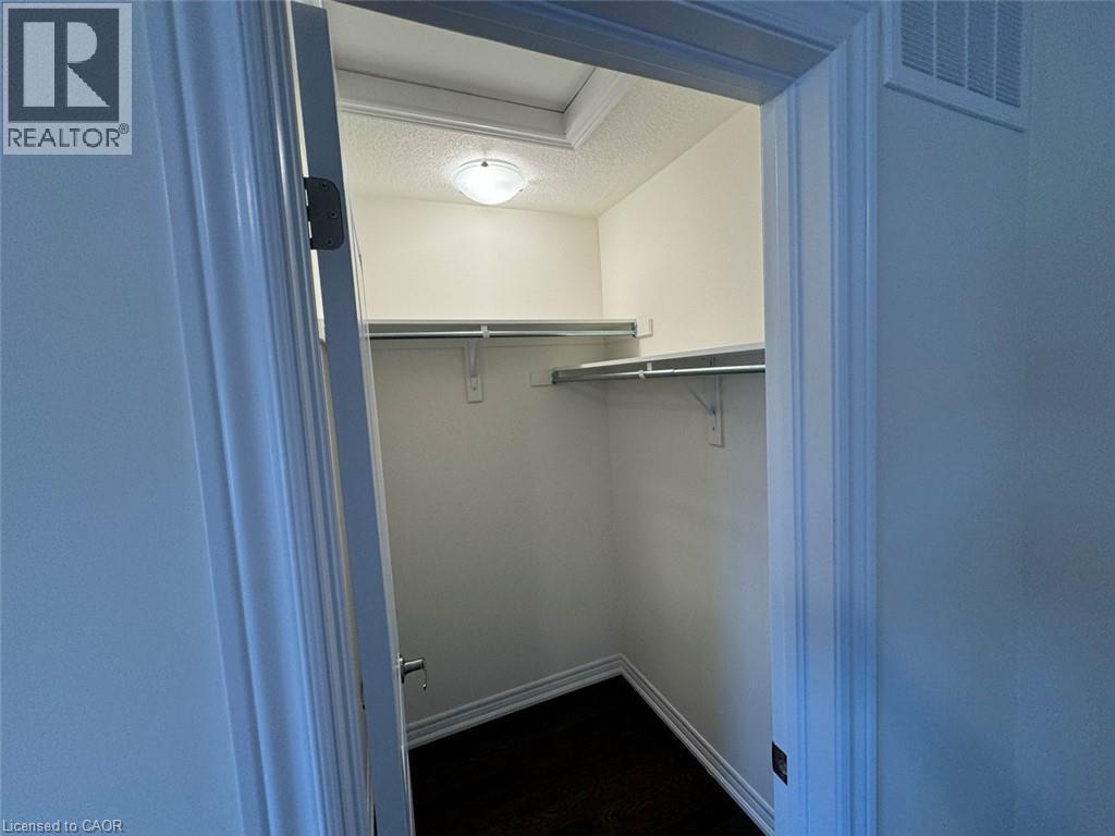 Walk-in closet featuring white walls, dark wood-finish flooring, and a ceiling-mounted light fixture - 10 Guernsey Drive Unit# Upper, Kitchener, ON