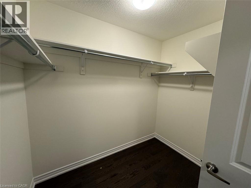 Well-lit closet featuring wood-finish flooring and extensive shelving with hanging rods - 10 Guernsey Drive Unit# Upper, Kitchener, ON