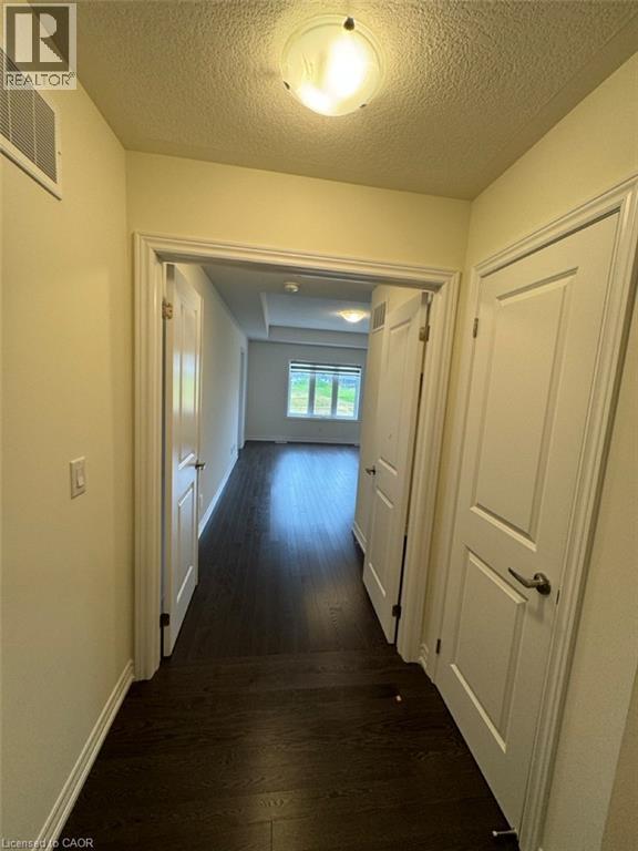 Hallway with dark wood-finish flooring, white trim, and a flush-mount ceiling light - 10 Guernsey Drive Unit# Upper, Kitchener, ON