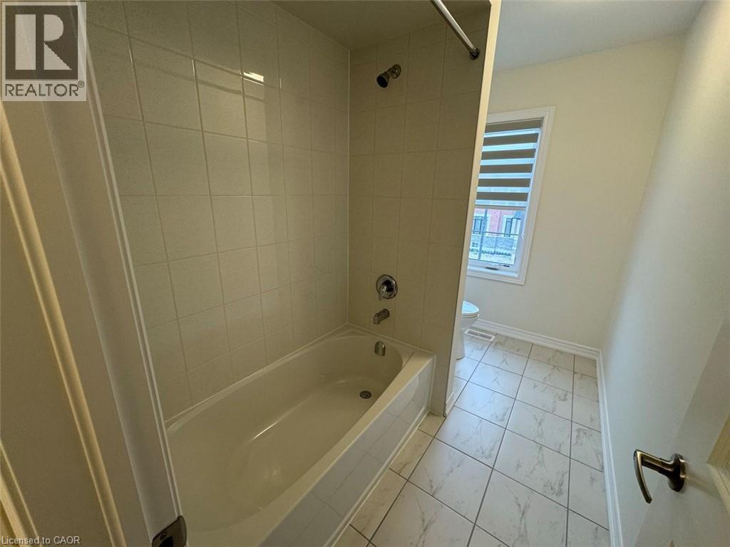 Full bathtub with chrome fixtures, surrounded by tiled walls - 10 Guernsey Drive Unit# Upper, Kitchener, ON