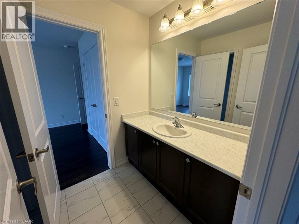 Bathroom vanity featuring a single sink, light-toned countertop, dark wood-finish cabinetry, and a large wall-mounted mirror - 10 Guernsey Drive Unit# Upper, Kitchener, ON