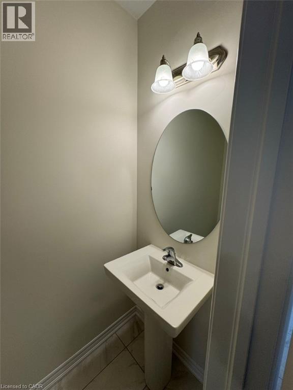 Pedestal sink with chrome faucet, complemented by an oval mirror and a two-light vanity fixture - 10 Guernsey Drive Unit# Upper, Kitchener, ON