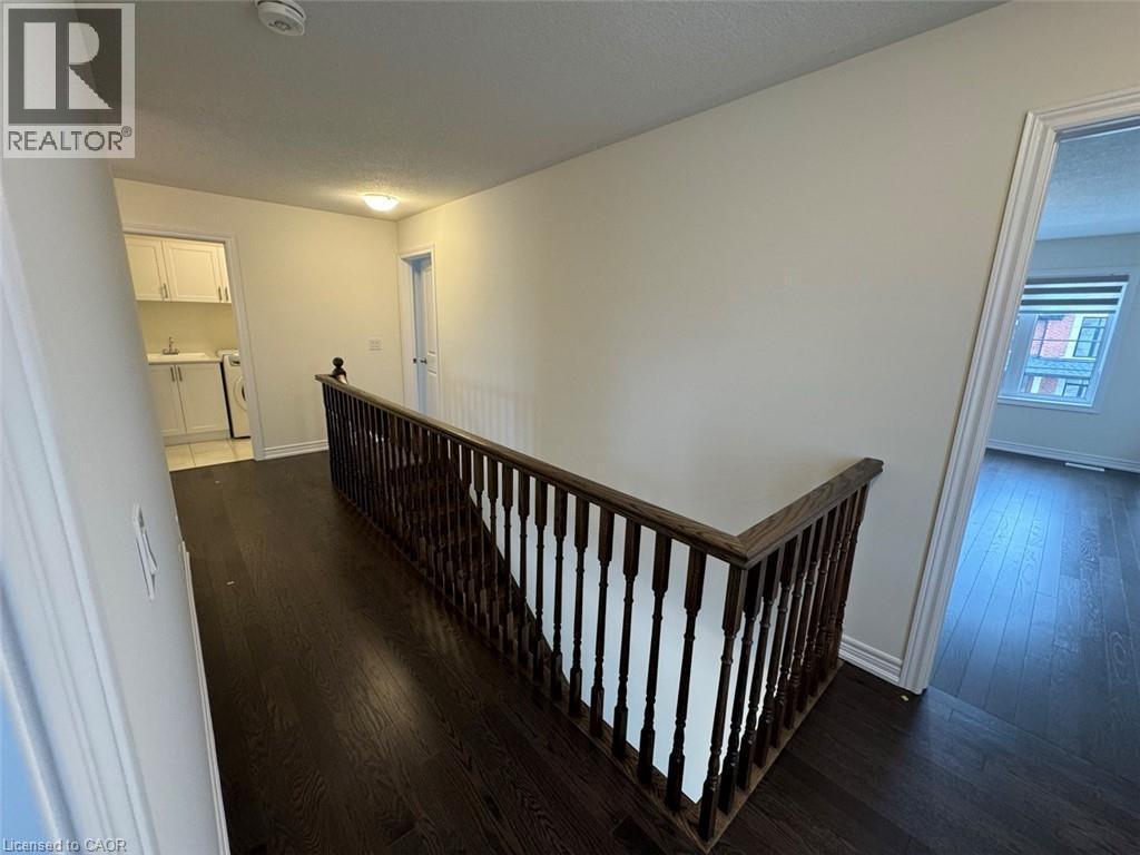 Upper-level landing featuring dark wood-finish flooring, a dark wood banister with white spindles, and light-toned walls - 10 Guernsey Drive Unit# Upper, Kitchener, ON