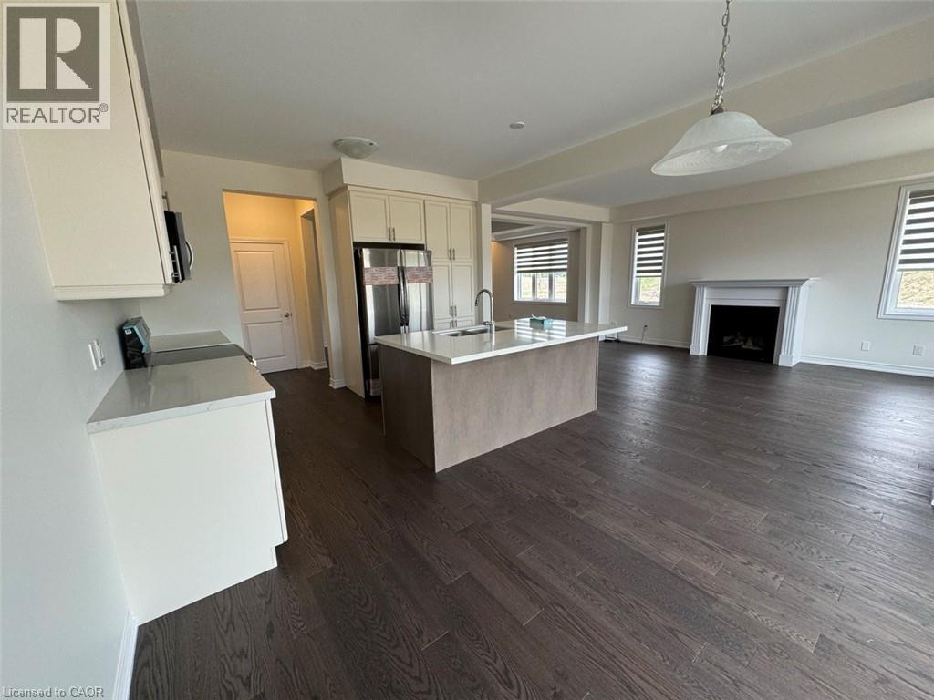 Open-concept living space with dark wood-finish flooring, featuring a modern kitchen island with seating, stainless steel appliances, and light-colored cabinetry - 10 Guernsey Drive Unit# Upper, Kitchener, ON