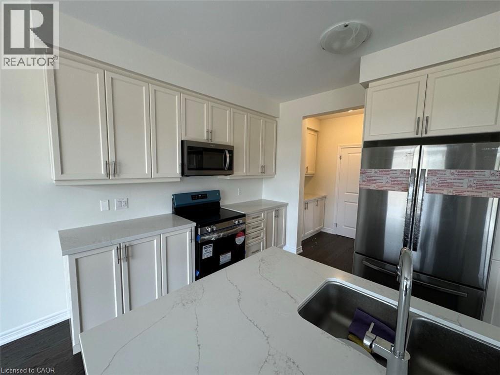 Modern kitchen featuring white shaker cabinetry, stainless steel appliances, a built-in microwave, and stone countertops - 10 Guernsey Drive Unit# Upper, Kitchener, ON