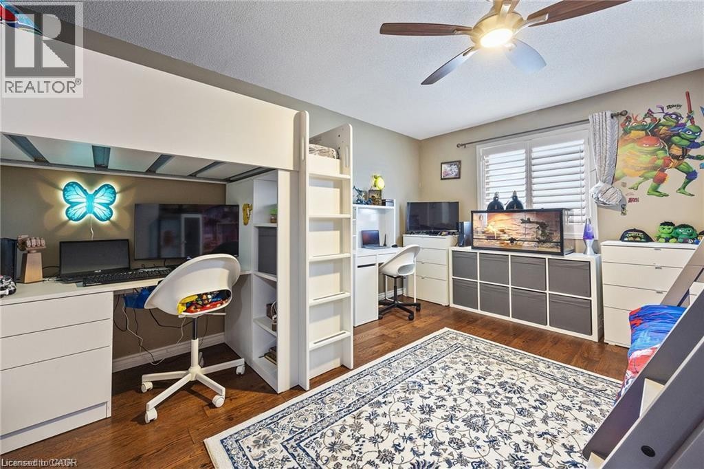 Loft bed with built-in desk and shelving, wood-finish flooring, ceiling fan with light fixture, and window with white louvered blinds - 125 Terni Boulevard, Hamilton, ON - Indoor