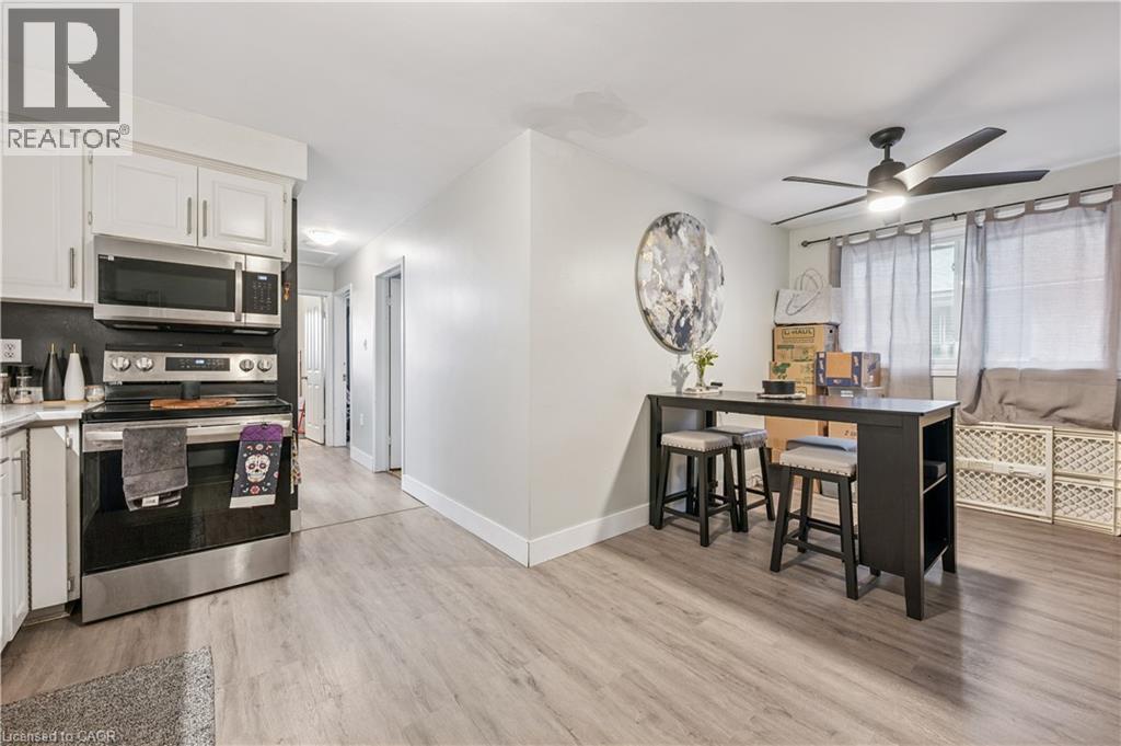 Contemporary kitchen featuring white cabinetry, stainless steel appliances, and wood-finish flooring - 35 Vicmount Drive, Kitchener, ON