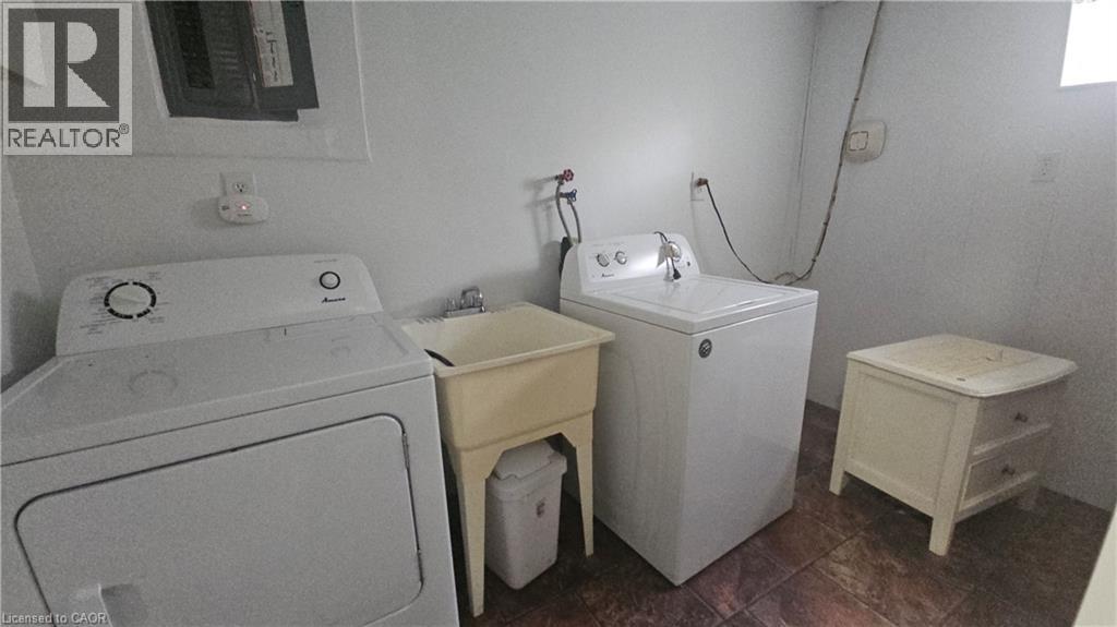 Dedicated utility area featuring a ceramic utility sink, white walls, and durable floor tiling - 58 Belwood Crescent, Kitchener, ON