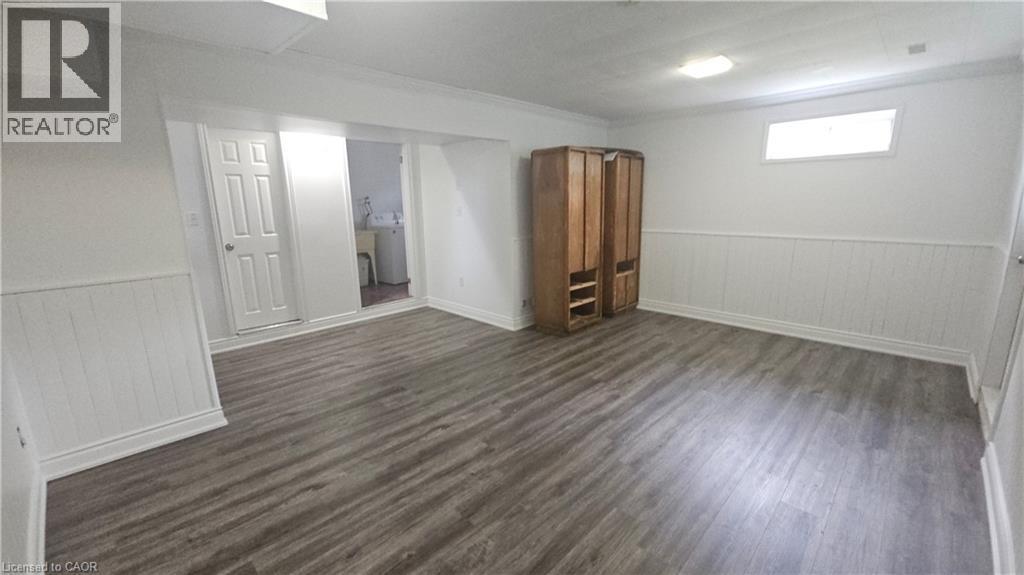 Spacious finished room with wood-finish flooring, white wainscoting, and recessed lighting - 58 Belwood Crescent, Kitchener, ON