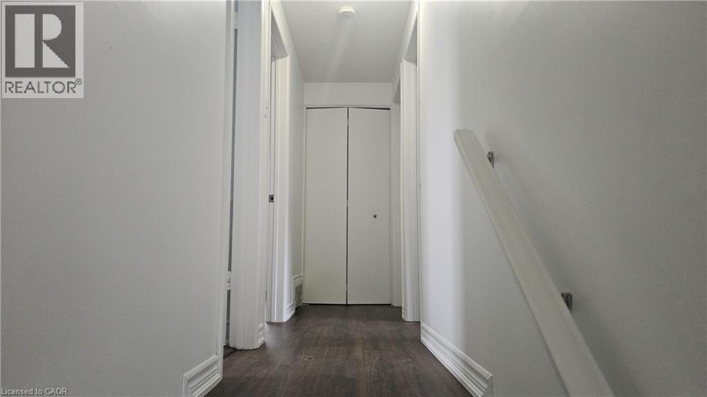 Hallway featuring wood-finish flooring, white walls, and bright white trim - 58 Belwood Crescent, Kitchener, ON