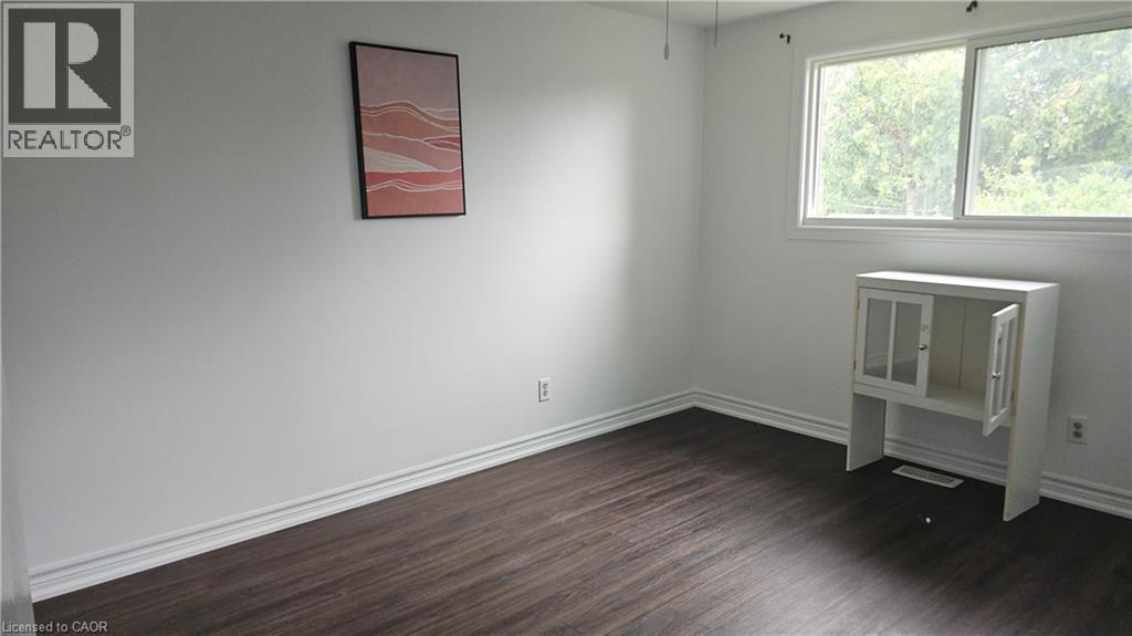 Interior room featuring wood-finish flooring, white baseboards, and light-colored walls - 58 Belwood Crescent, Kitchener, ON