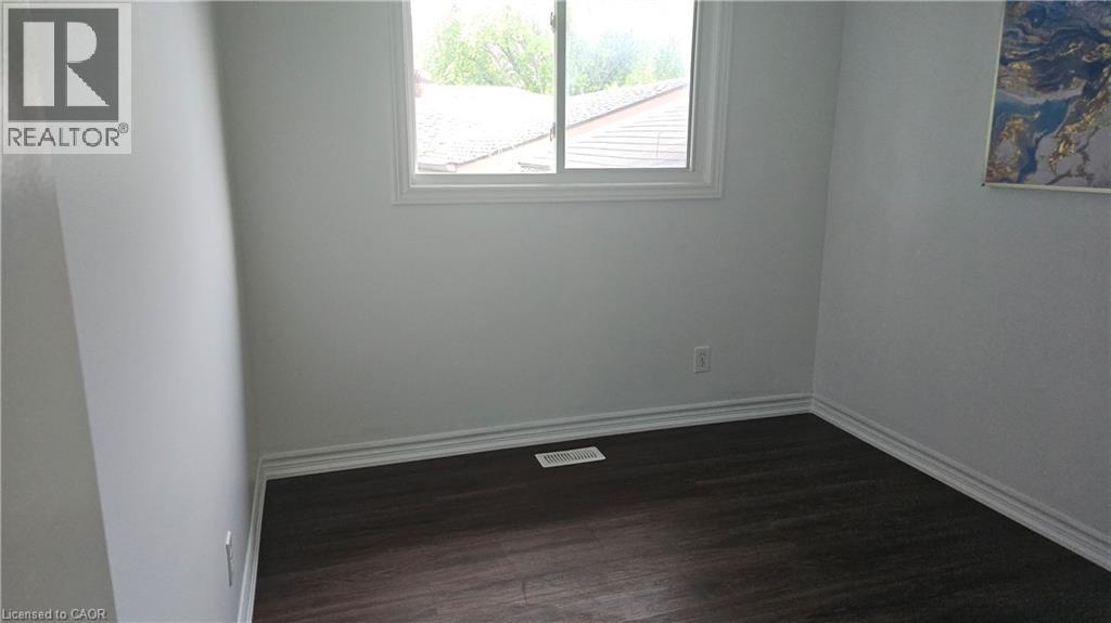 Room featuring dark wood-finish flooring, white baseboards, and light-toned walls - 58 Belwood Crescent, Kitchener, ON