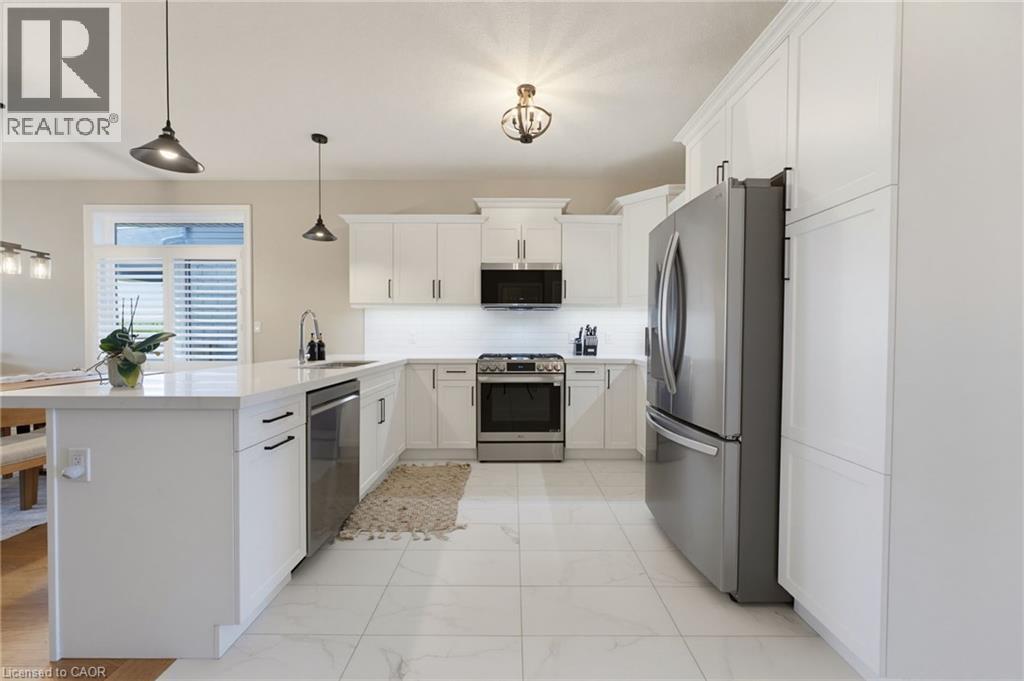 The heart of the home, this stunning open concept kitchen offers quartz countertops, soft close cabinetry, stainless steel appliances, and seamless flow into the dining and living areas. - 131 Craddock Boulevard, Haldimand, ON