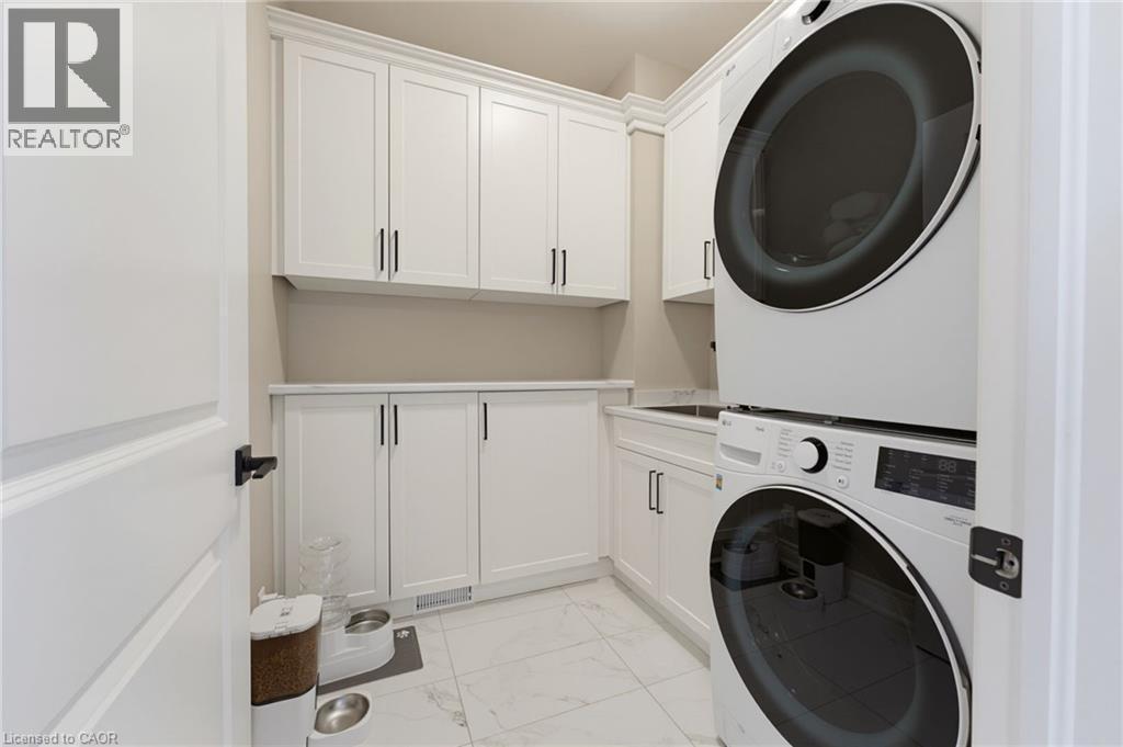 Spacious main floor laundry room with extensive custom cabinetry and built in storage, sink and a folding counter - 131 Craddock Boulevard, Haldimand, ON
