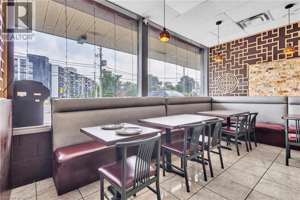 Commercial dining space featuring large storefront windows, tiled flooring, upholstered booth seating, decorative wall paneling, and pendant lighting fixtures - 155 Highland Road E, Kitchener, ON