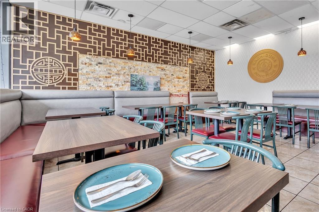 Spacious dining area featuring booth seating, wood-finish tables, pendant lighting, textured wall accents, and tiled flooring - 155 Highland Road E, Kitchener, ON