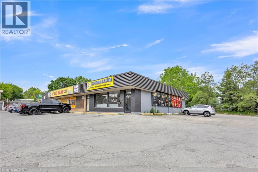 Commercial building featuring a dark exterior facade with contrasting yellow signage - 155 Highland Road E, Kitchener, ON