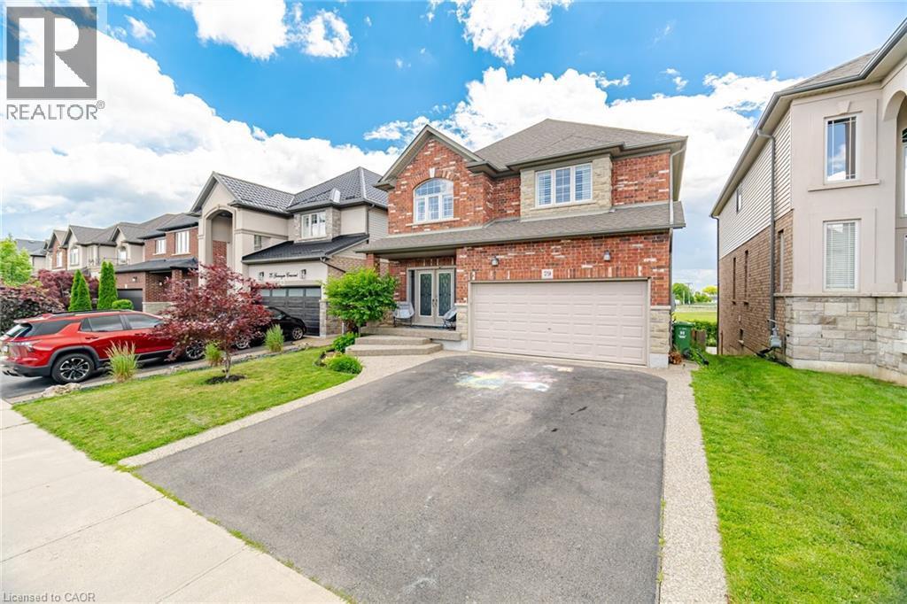 Traditional brick and stone facade residence featuring a two-car garage, asphalt driveway, and a concrete pathway to the main entry - 79 Garinger Crescent, Hamilton, ON