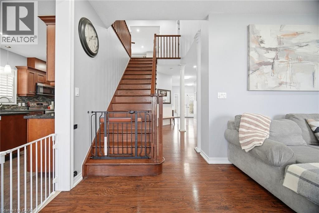 Rich wood-finish flooring extending through the entry and up the staircase - 79 Garinger Crescent, Hamilton, ON