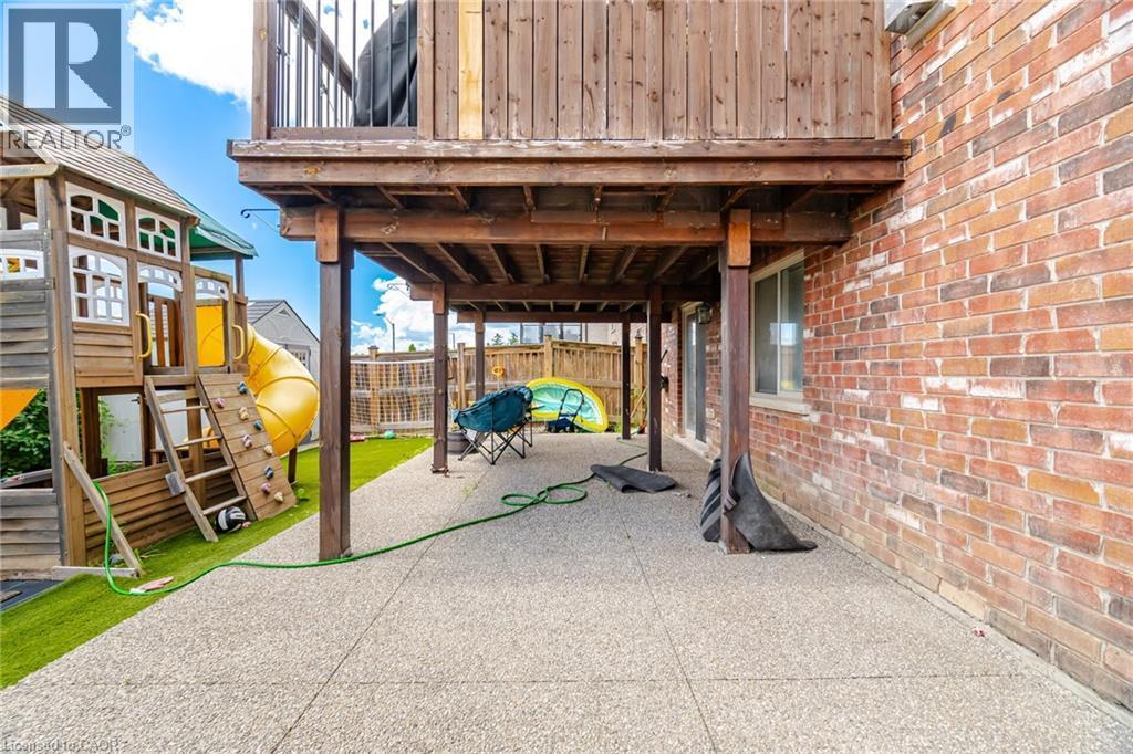 Ground-level patio featuring an exposed aggregate surface and overhead deck structure - 79 Garinger Crescent, Hamilton, ON