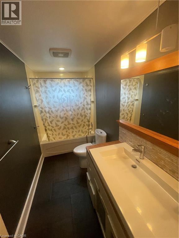 Bathroom featuring a vanity with integrated sink, a rectangular mirror with wood-tone framing, and modern wall sconces - 134 Bridgeport Road E Unit# Upper, Waterloo, ON