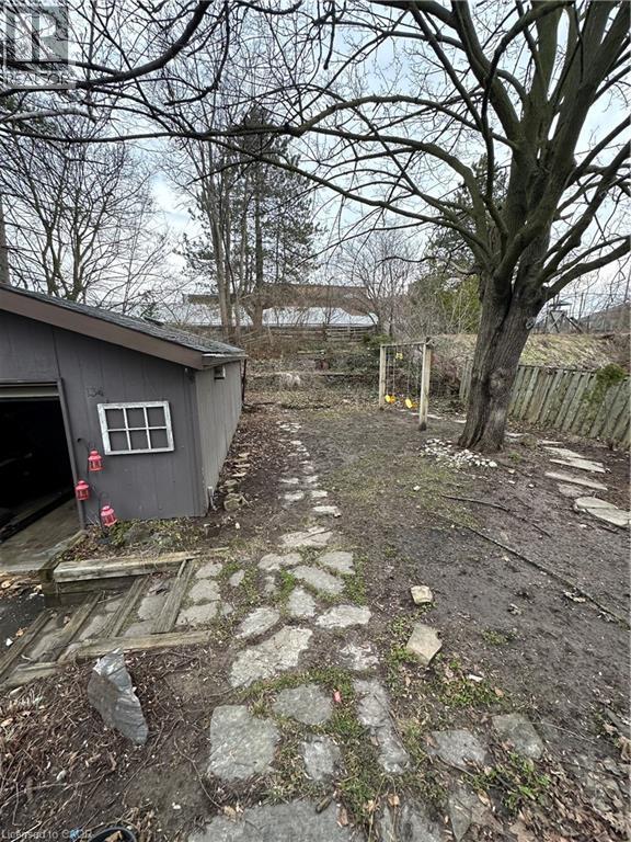 Expansive outdoor area featuring a stone pathway, a mature tree, and a detached shed with a window - 134 Bridgeport Road E Unit# Upper, Waterloo, ON