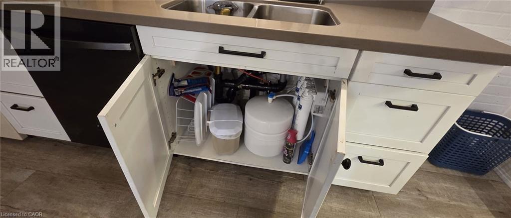 White shaker-style cabinetry featuring black hardware, a double basin stainless steel sink, and a dark countertop - 134 Bridgeport Road E Unit# Upper, Waterloo, ON