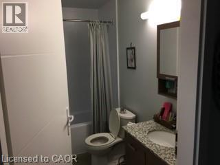 Bathroom featuring a white tub, toilet, and a vanity with a granite-style countertop and integrated sink - 280 Lester Street Unit# 607, Waterloo, ON