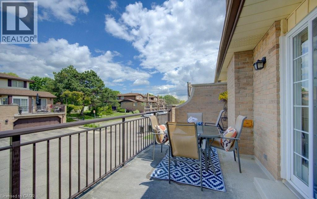Spacious outdoor terrace with a concrete surface, featuring a black metal railing and a beige brick exterior - 458 Beechwood Place Unit# 3, Waterloo, ON - Outdoor With Exterior