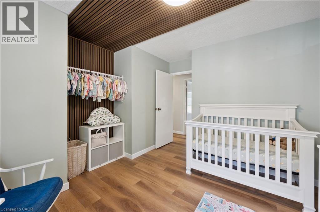 Interior room featuring wood-finish flooring, a wood slat accent wall, and a textured ceiling - 2 Keewatin Avenue, Kitchener, ON