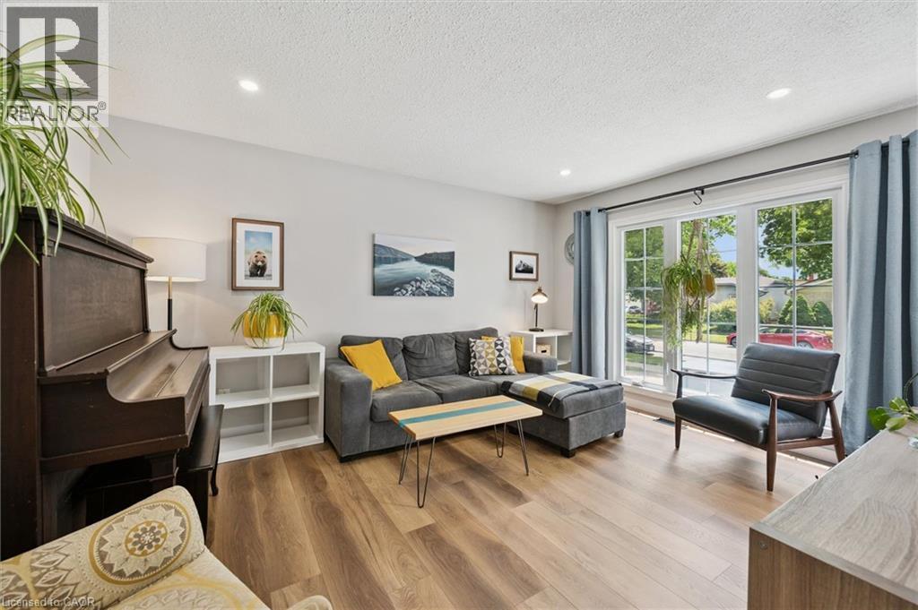 Spacious interior featuring wood-finish flooring, recessed lighting, and a large window with white framing - 2 Keewatin Avenue, Kitchener, ON
