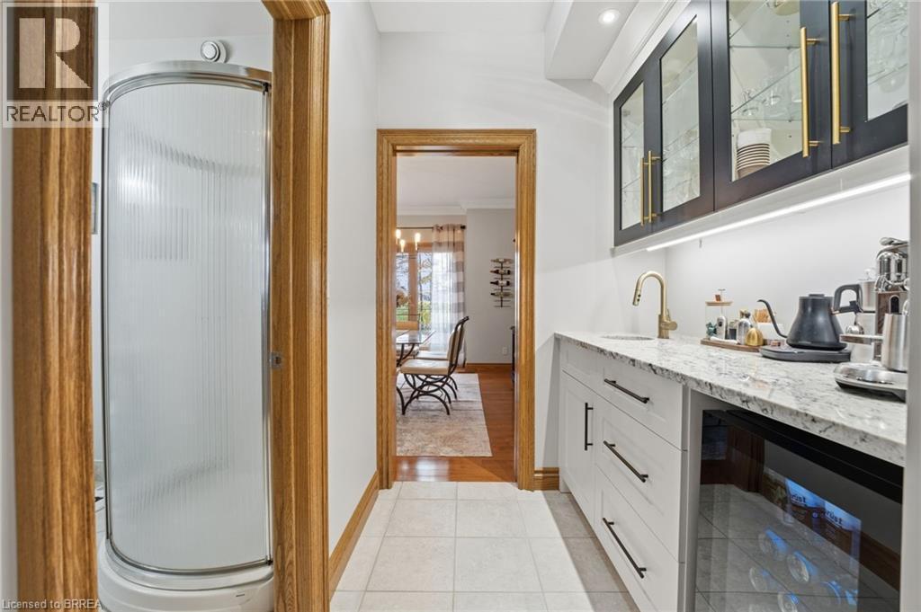 Custom built-in wet bar featuring white cabinetry, a granite-finish countertop, and a brass-finish faucet - 271 Windham Rd 14, Simcoe, ON