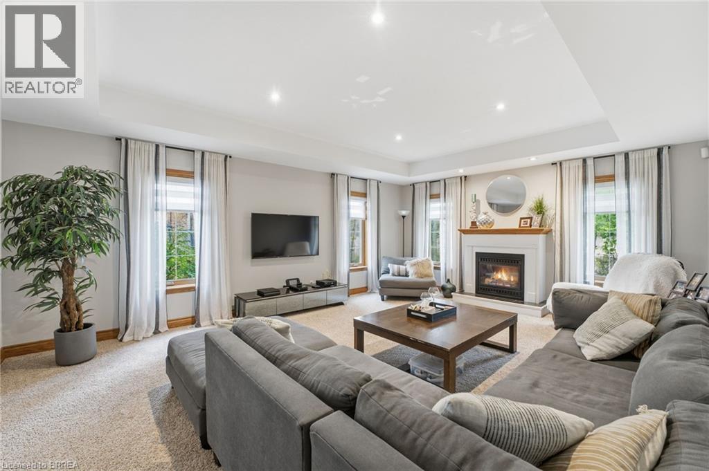 Living area featuring a gas fireplace with a white mantel, recessed lighting, crown molding, and light-toned carpeting - 271 Windham Rd 14, Simcoe, ON