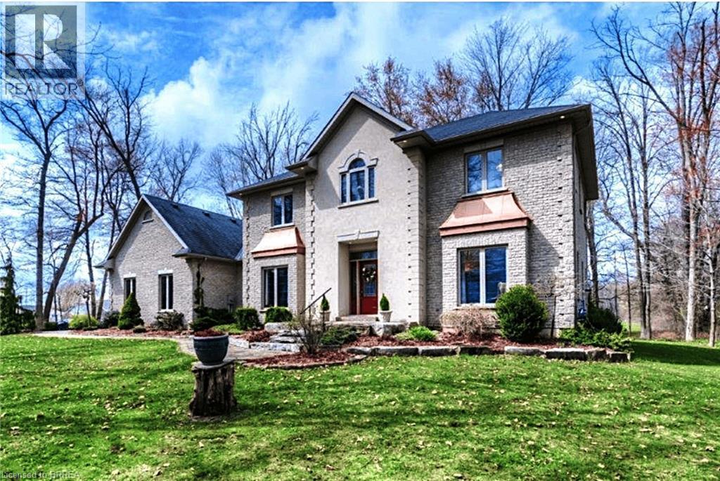 Stately residence featuring a stone and stucco exterior, multiple gables, a prominent entry, and a front yard with mature landscaping - 271 Windham Rd 14, Simcoe, ON
