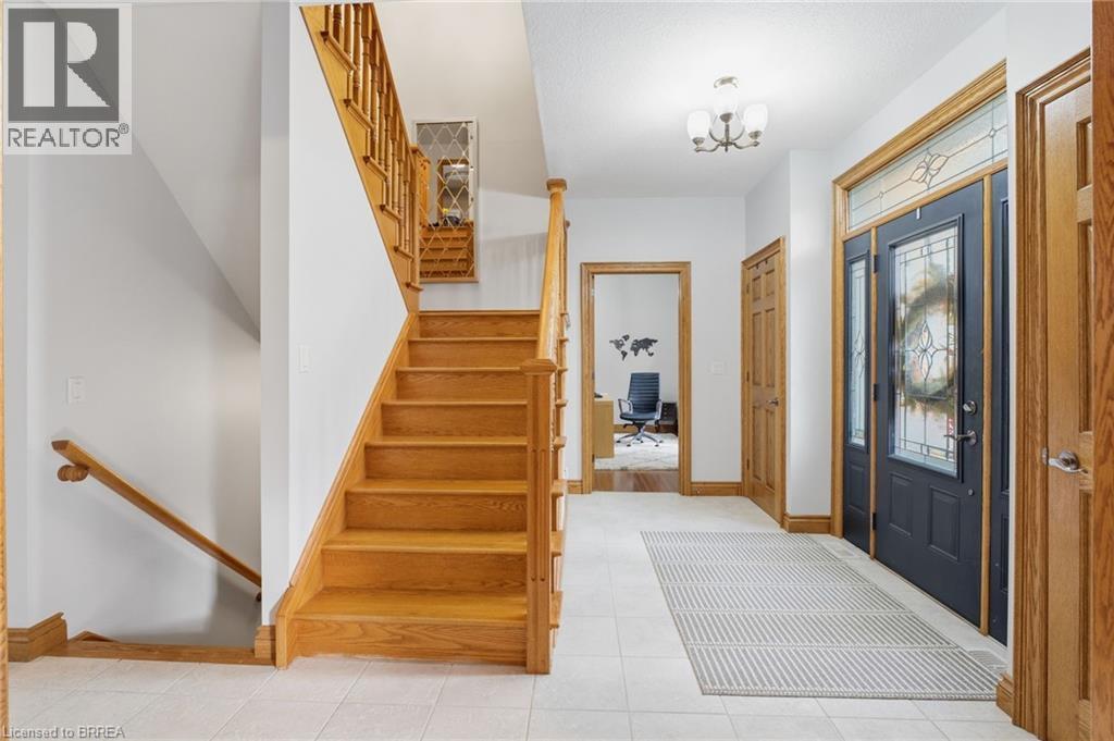 Foyer featuring a wood-finish staircase with matching banister, panel doors, and trim - 271 Windham Rd 14, Simcoe, ON